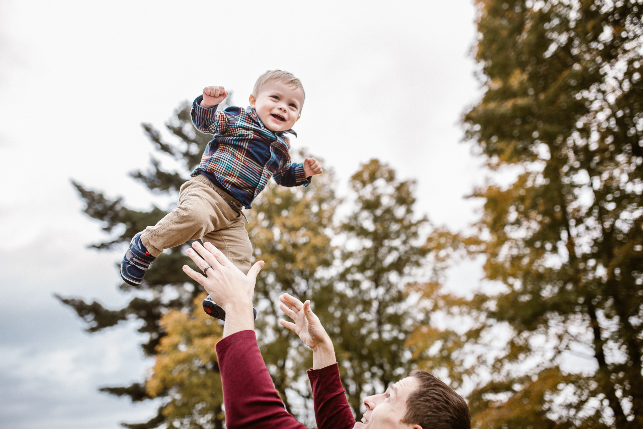 Toddler boy being tossed into the air by his father.