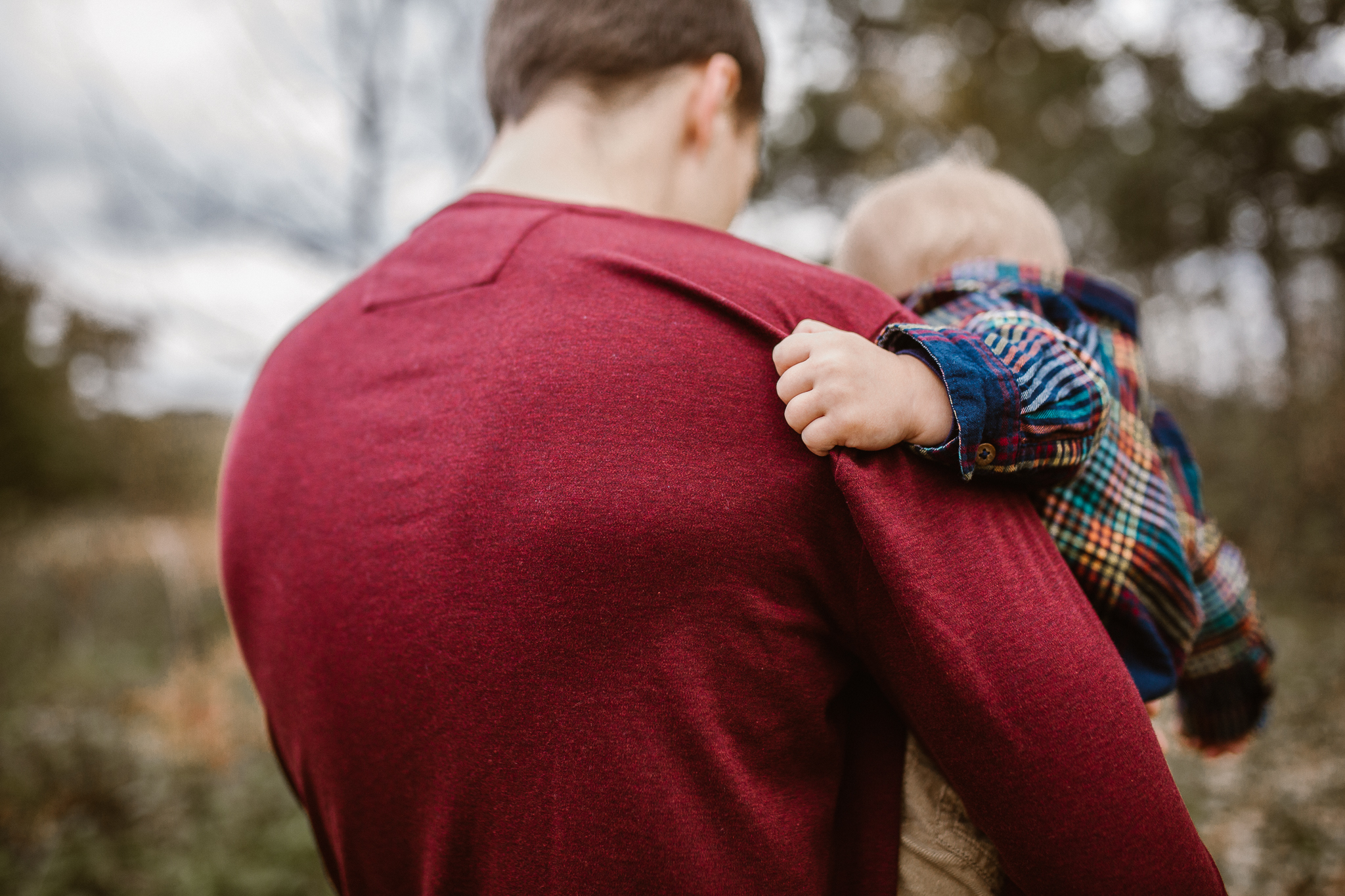 Toddler boy grasping onto his father's sweater.