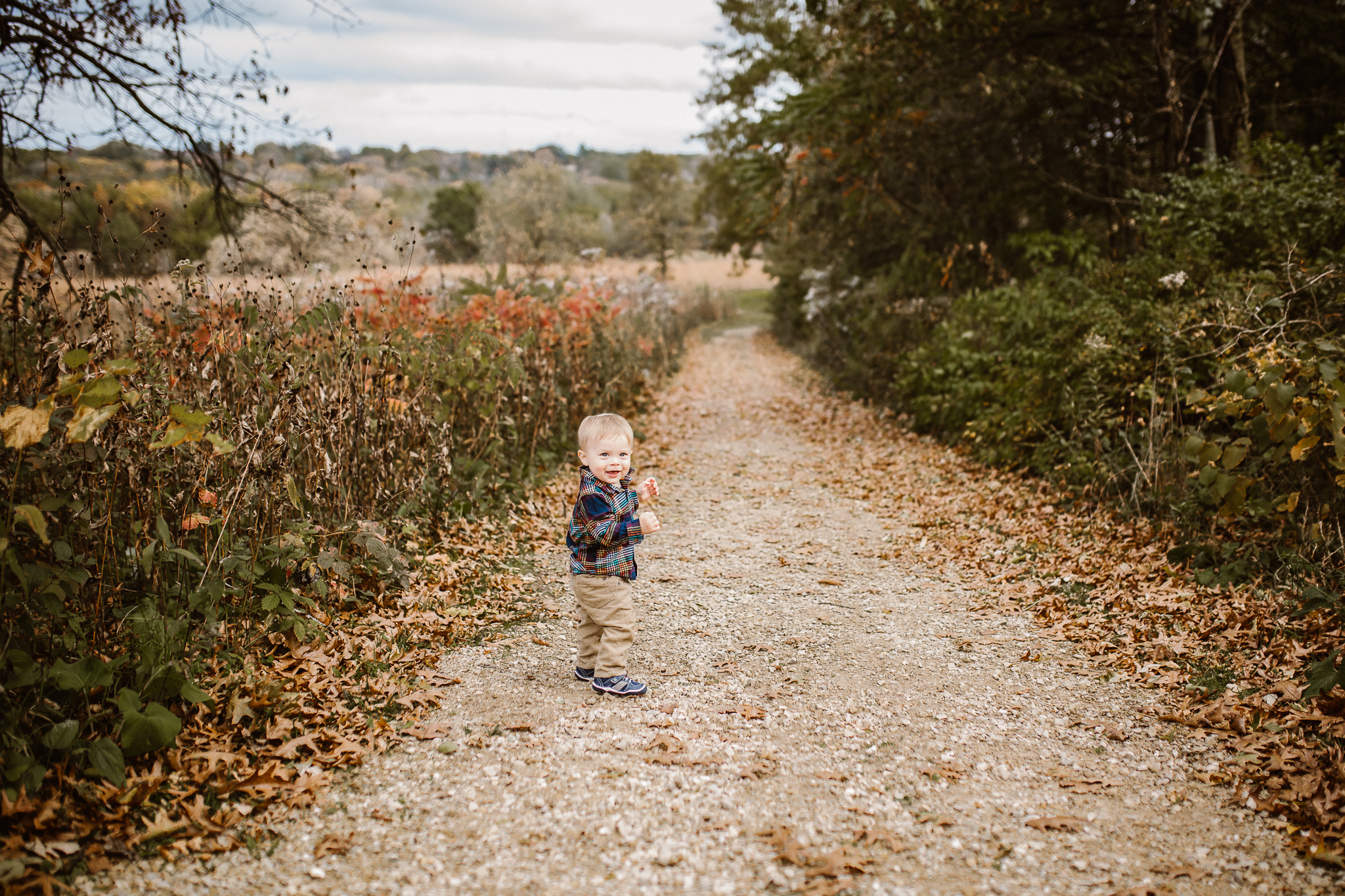 Toddler boy wandering on a gravel path in autumn.